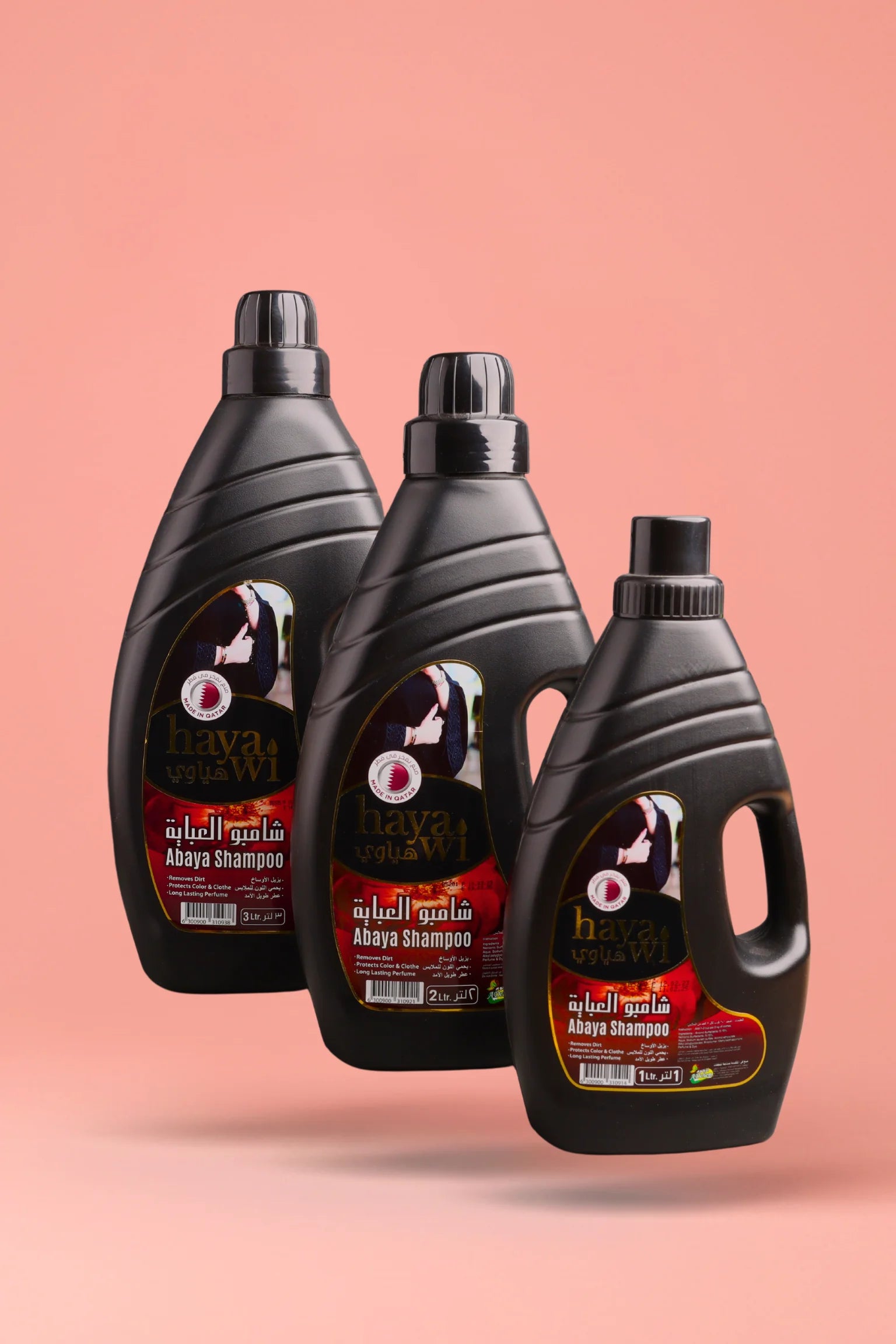 Three bottles of Hayawi Abaya shampoo with a pink background