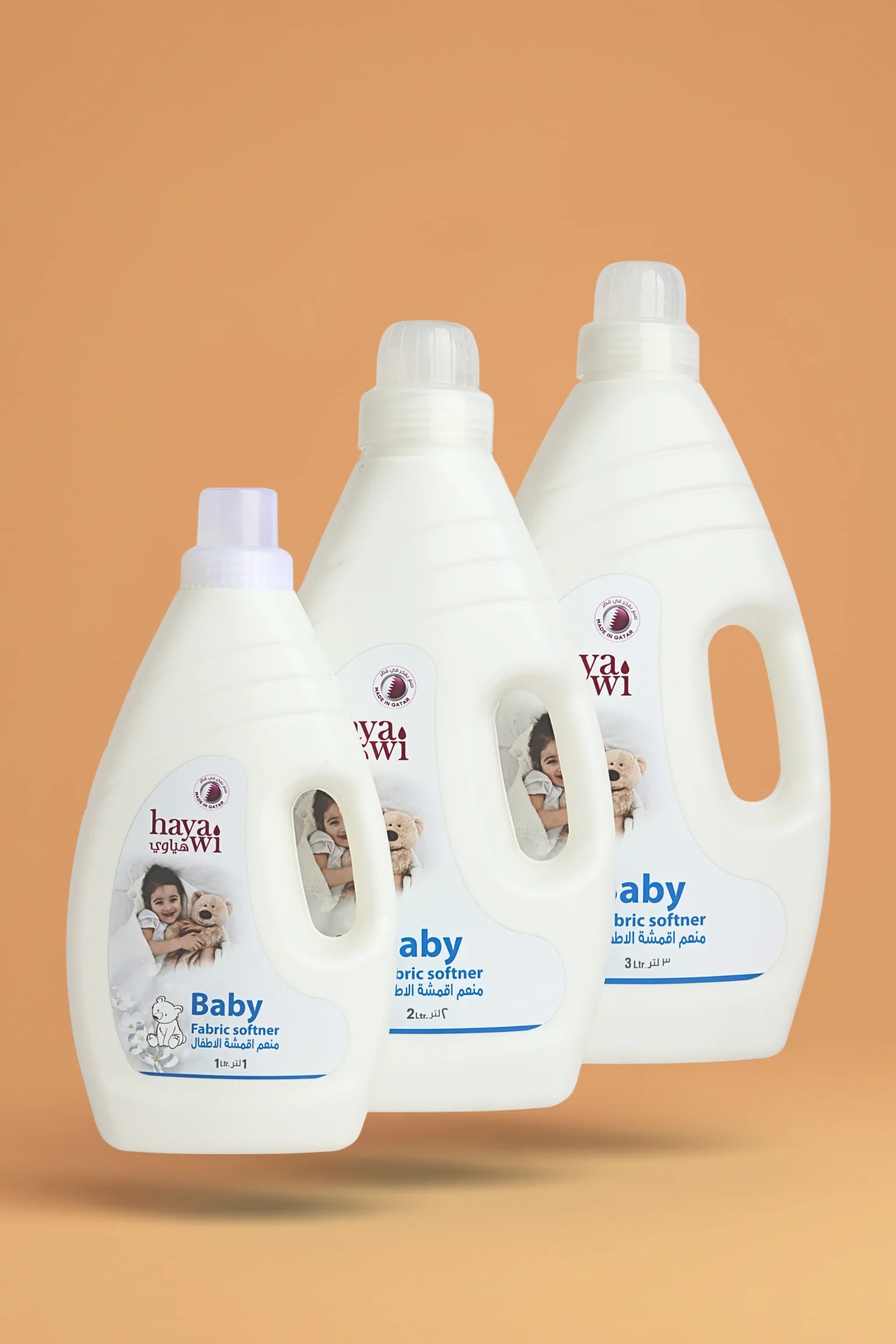 Three bottles of baby fabric softener on a beige background